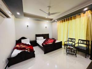 1 dormitorio con 2 camas y 2 sillas en Imperial lodges, en Islamabad