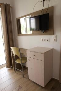 キオタリにあるSeaside Studios Kiraniaのテーブルと椅子、壁にテレビが備わる客室です。