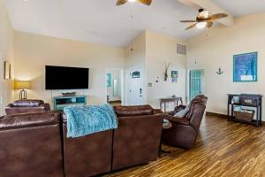 a living room with leather furniture and a flat screen tv at Bay Haven on Copano- 4 bdrm w/ 200+ft Fishing Pier in Rockport