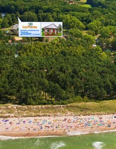 un groupe de personnes sur une plage avec parasols dans l'établissement Domki Letniskowe Las Palmas Dąbki, à Dąbki