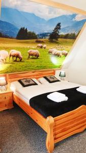 een slaapkamer met een groot schilderij van schapen in een veld bij Willa na górskim szlaku in Ciche Małe