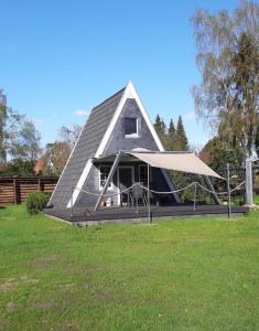 una casa con un techo inclinado en un campo de césped en Ferienhaus Elbliebe - kleine Hunde bis 25 cm willkommen en Dannenberg