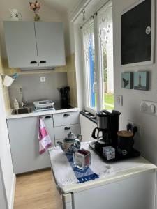 a kitchen with white cabinets and a sink and a table at Penty de Mézareun in Ouessant +4 photos