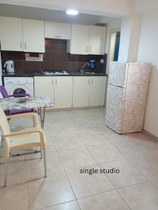 a kitchen with white cabinets and a table and a refrigerator at The Tony in Nicosia