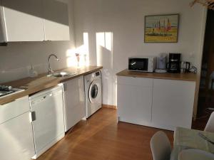 a kitchen with white cabinets and a washer and dryer at L établissement Gold Beach propose 1 maison 80m2 avec terrain 500m2 PARKING PRIVE à 4 min du port artificiel d ARROMANCHES SERVICES Accueil personnalisé lits faits serviettes ménage NETFLIX wifi SUR VELOROUTE in Ryes