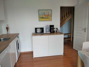 a kitchen with a counter with a microwave at L établissement Gold Beach propose 1 maison 80m2 avec terrain 500m2 PARKING PRIVE à 4 min du port artificiel d ARROMANCHES SERVICES Accueil personnalisé lits faits serviettes ménage NETFLIX wifi SUR VELOROUTE in Ryes +17 photos