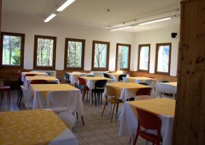 a dining room with tables and chairs and windows at Foresteria Miramonti affittacamere in Fiavè