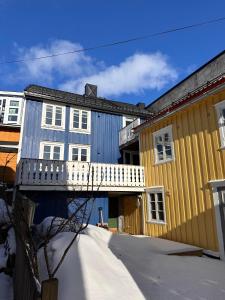 a yellow house and a blue building with a balcony at Tidligere stall omgjort til koselig hjem i sentrum in Tromsø