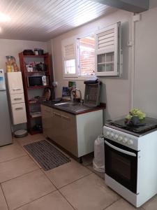 a kitchen with a stove and a sink and a refrigerator at Sous le manguier in Sainte-Anne