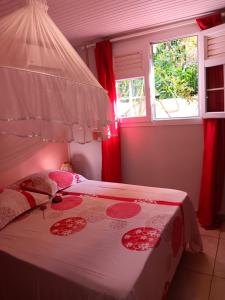 a bedroom with a large bed with red curtains at Sous le manguier in Sainte-Anne