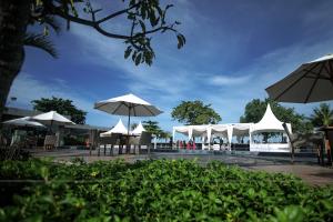 un groupe de parasols blancs, de tables et de chaises dans l'établissement Pangeran Beach Hotel, à Padang