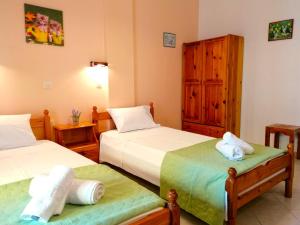 a bedroom with two beds and a wooden cabinet at Nikos Apartments 2 in Kavos