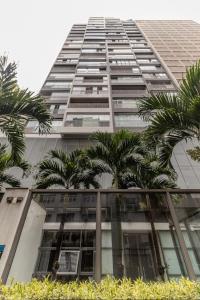 a tall building with palm trees in front of it at Consolação Estúdio 127 in Sao Paulo