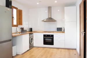 a kitchen with white cabinets and a washer and dryer at Mar de fonts ain in Ahín