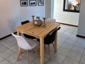 a wooden table with chairs and a vase on it at Beacon Point in Mossel Bay