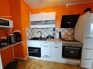 a kitchen with white cabinets and an orange wall at Sous les Etoiles - dans le plus haut gratte-ciel avec parking in Rouen