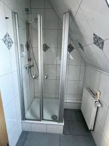 a shower with a glass door in a bathroom at Pension Kolibri in Hemmoor