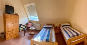 Habitación pequeña con 2 camas y TV. en Pension Kolibri, en Hemmoor