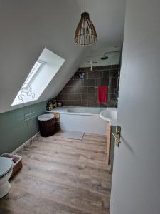 ein Bad im Dachgeschoss mit einer Badewanne und einem Waschbecken in der Unterkunft Chez Gilles et Isabelle in Cairon