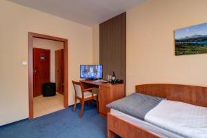 um quarto com uma cama e uma secretária com uma televisão em LC - Hotel Ostrava em Ostrava