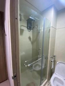 La salle de bains est pourvue d'une douche en verre et de toilettes. dans l'établissement S residences Pasay , near Mall of Asia, à Manille