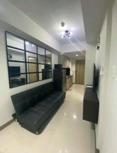 - un canapé noir dans une chambre avec une grande fenêtre dans l'établissement S residences Pasay , near Mall of Asia, à Manille