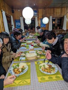 Lukla Himalaya Lodge في Lukla: مجموعة من الناس يجلسون على طاولة طويلة يأكلون الطعام