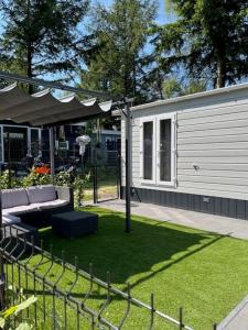 un jardin avec un canapé, une clôture et une maison dans l'établissement Het Zonnige Veluwshofje, à Hoenderloo