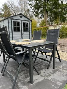 - une table de pique-nique avec 2 chaises et une cabane pour chiens dans l'établissement Het Zonnige Veluwshofje, à Hoenderloo