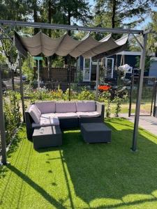 un canapé assis sur l'herbe sous un kiosque dans l'établissement Het Zonnige Veluwshofje, à Hoenderloo