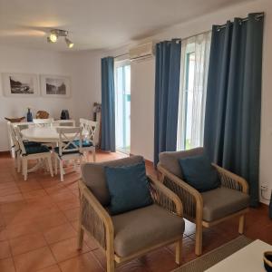 a living room with blue curtains and a table and chairs at ALVOR VILLAGE BY THE SEA in Alvor