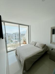 a white bedroom with a bed and a large window at Nuevo, amoblado y las mejores vistas de amaneceres in Santa Marta