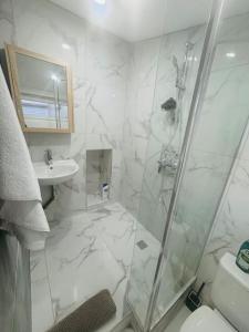 ein weißes Bad mit einer Dusche und einem Waschbecken in der Unterkunft Studio meublé in Marseille
