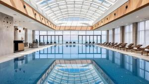 a large swimming pool with chairs and a glass ceiling at Black Sea Luxury Apartment in Batumi