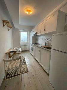 uma cozinha com armários brancos, uma mesa e um frigorífico em Fancy apartament Silk district em Iaşi