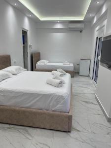 a bedroom with two beds and a flat screen tv at Harmony Apartments in Dhërmi