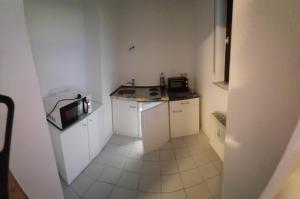 een kleine keuken met witte kasten en een magnetron bij feel-good-appartements in Karlsruhe