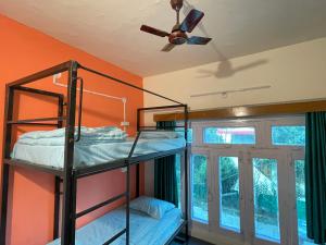 a room with two bunk beds and a ceiling fan at RAMARHYTHMS in Mukteswar
