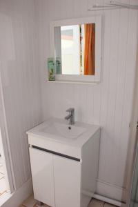 een witte badkamer met een wastafel en een spiegel bij Le carambolier maison avec vue imprenable in La Trinité
