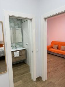 a bathroom with an orange couch and a sink at Orange Suite by Alhaurín Loft City Center in Alhaurín de la Torre