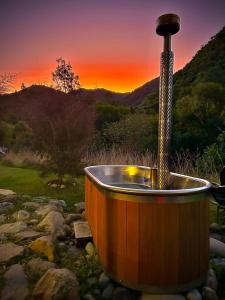a wooden tub with a shower in a field at Alpacas Off Grid - Eco Cabin in Takaka