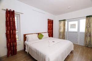 a bedroom with a white bed and two windows at Seven Endue Delight with Mountain view on the Hill Top in Ooty