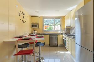 a kitchen with yellow cabinets and a table with red chairs at Calidad-precio un 10, Apartamento maravilloso in Tossa de Mar