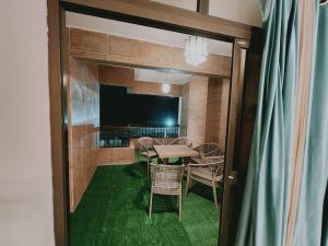 ein Esszimmer mit Tisch, Stühlen und grünem Teppich in der Unterkunft Panorama sea view Domino's house in Alexandria