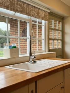 a kitchen counter with a sink and two windows at 'BRAMLEY FALL COTTAGE', CHILD FRIENDLY, 3 Separate Bedrooms -1 on ground level, SLEEPS 6, 2Bathrooms, Wittering Beach 8min drive, Rural Location, Private Parking in Chichester