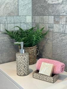 a bathroom counter with a soap dispenser and a plant at Situated in Stunning Highleigh Village,'BRAMLEY FALL COTTAGE'-Attached Cottage,3 Bedrooms-1 on ground level, SLEEPS 6-2 Bathrooms, 9 mins to Sandy Wittering Beach, 5 mins from Southend Barns, Child friendly,Small Breed Dog Friendly 2 max, Parking-EV Point in Chichester