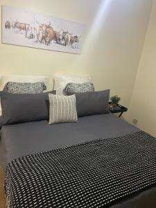 a bed with a black and white comforter in a bedroom at Sgele Guesthouse & Events in Vryheid