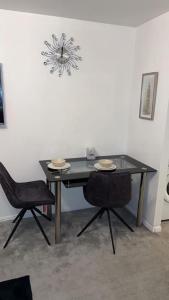 a black table with two chairs and a clock on the wall at Lovely Modern One bedroom Flat close to station in Belvedere