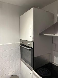 a small kitchen with a stove and white cabinets at Lovely Modern One bedroom Flat close to station in Belvedere