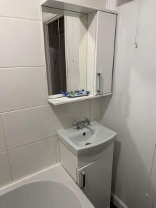 a white bathroom with a sink and a mirror at Lovely Modern One bedroom Flat close to station in Belvedere